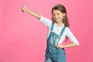 A girl in dungarees giving a thumbs up