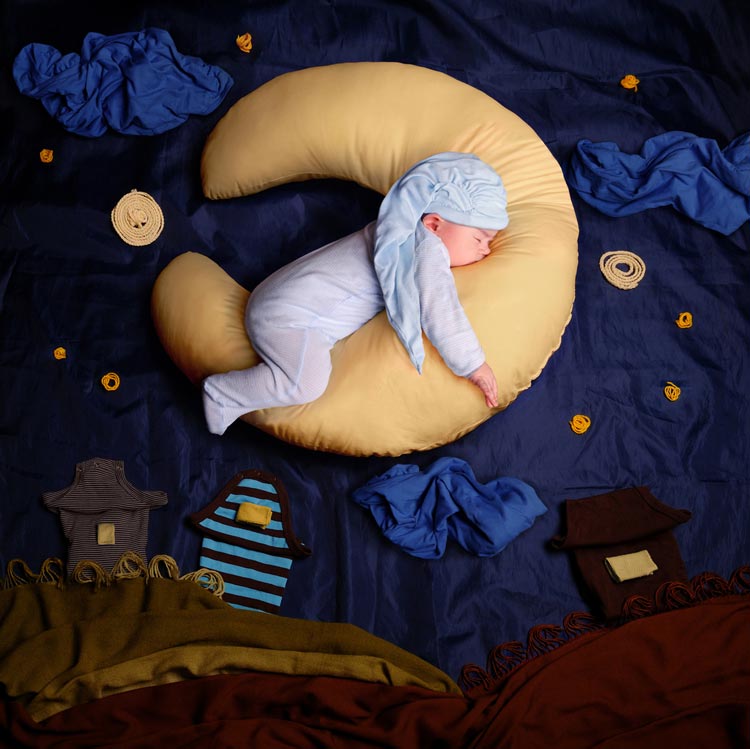 Baby sleeping on a pillow shaped like a half-moon