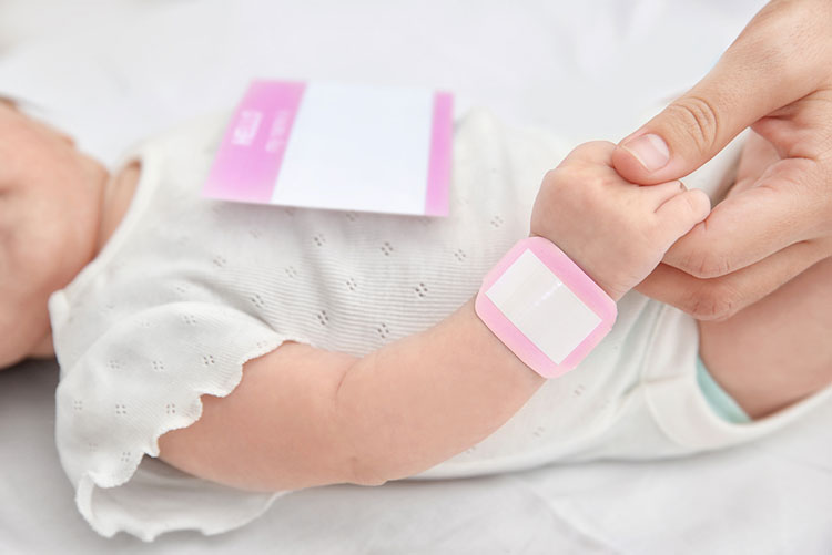 Baby with a nametag on it's dress and hand