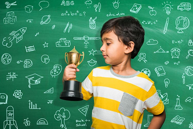 A young Hindu boy holding up a trophy.