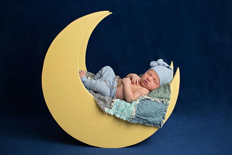 A baby made to sleep on a moon-shaped chair.