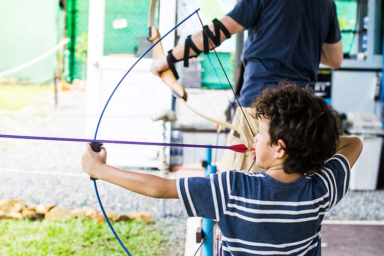 A young boy using a bow and arrow.