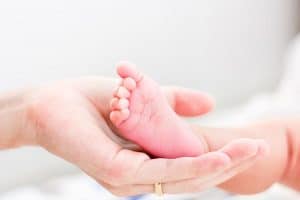 A mother holding her newborn's tiny foot.