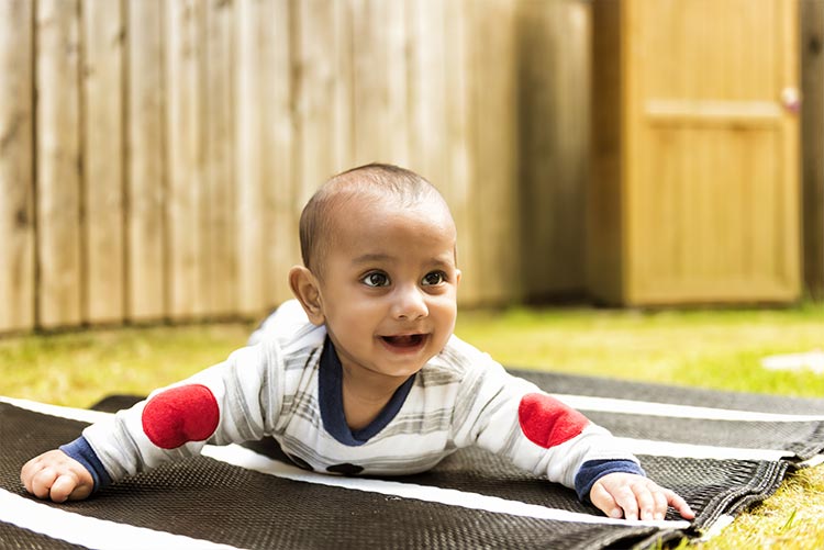 A baby boy lying down in his backyard.