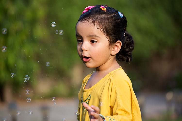 A girl playing around water bubbles.