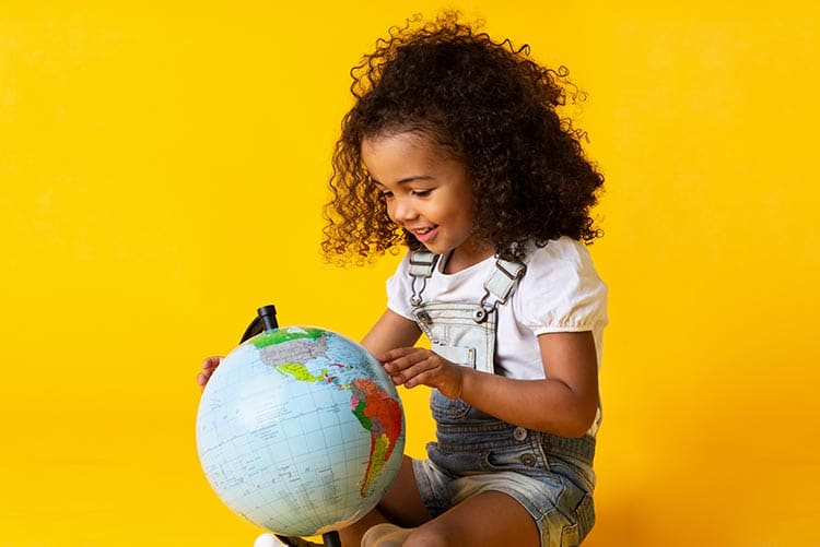 A girl looking at countries on a globe.