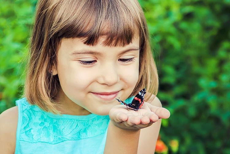 A little girl holding a butterfly.