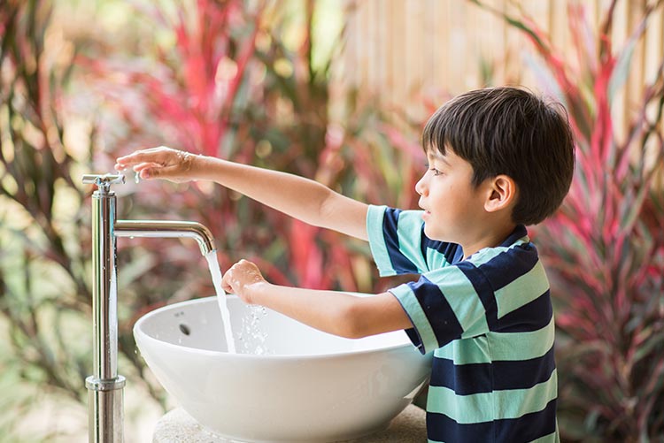 A young boy maintaining hygiene by washing hands.