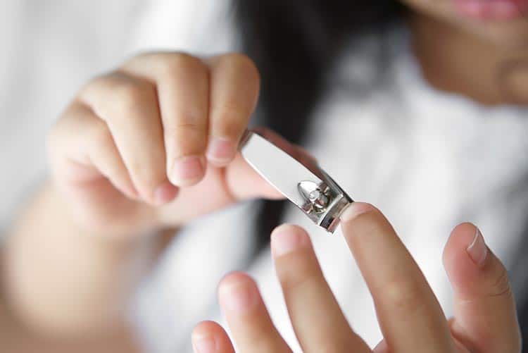 A young girl trimming her nails.