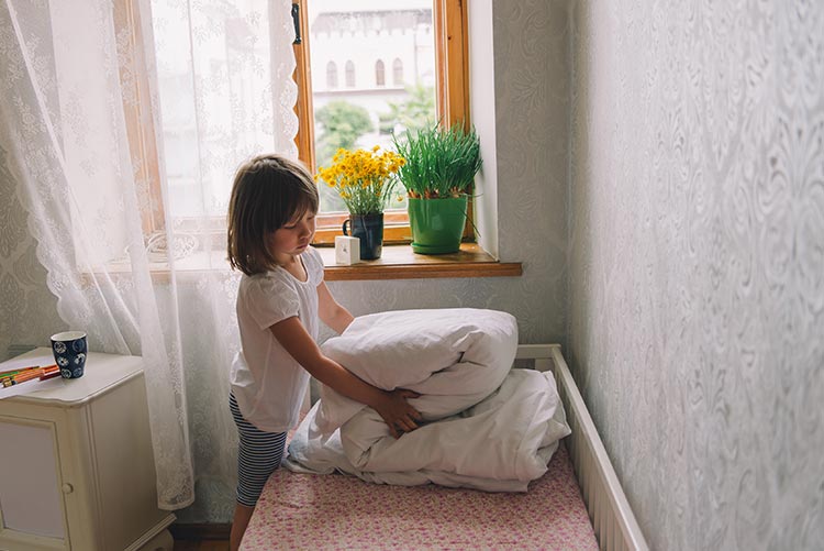 A girl making her bed in the morning.