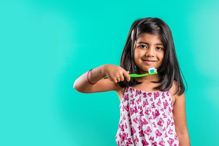 A young girl maintaining personal hygiene by brushing her teeth.
