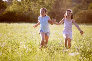 Two girls running in a field.
