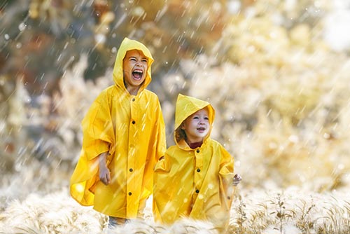 Two boys wearing head-to-toe raincoats.