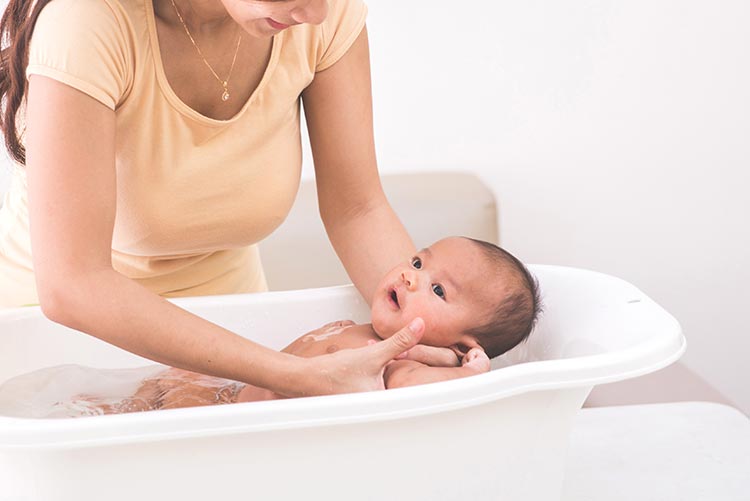 A mother carefully giving her newborn a baby bath.