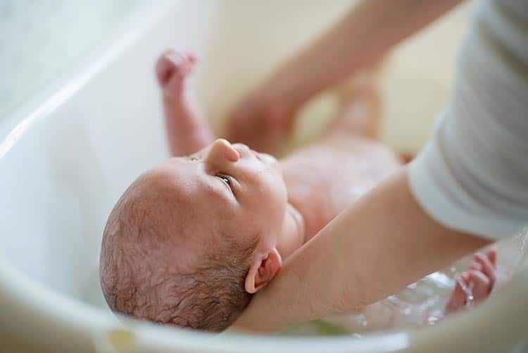 A mother giving her newborn a baby bath.