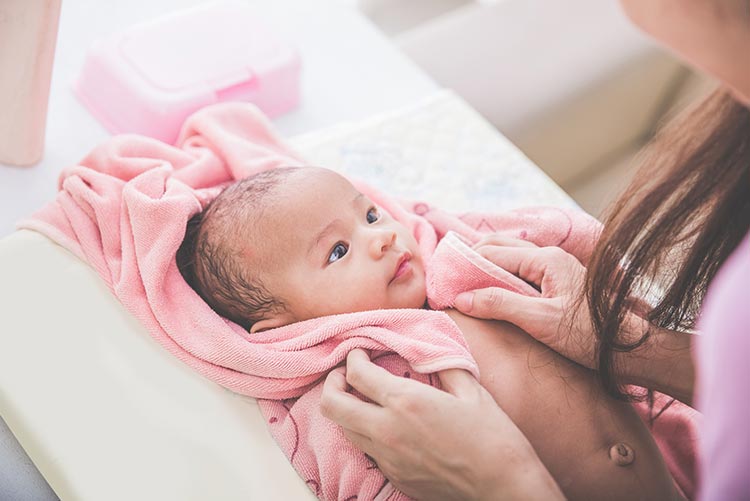 A lady patting her baby dry after a baby bath.