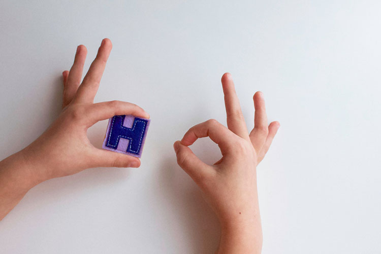 Hands holding the letter 'H'