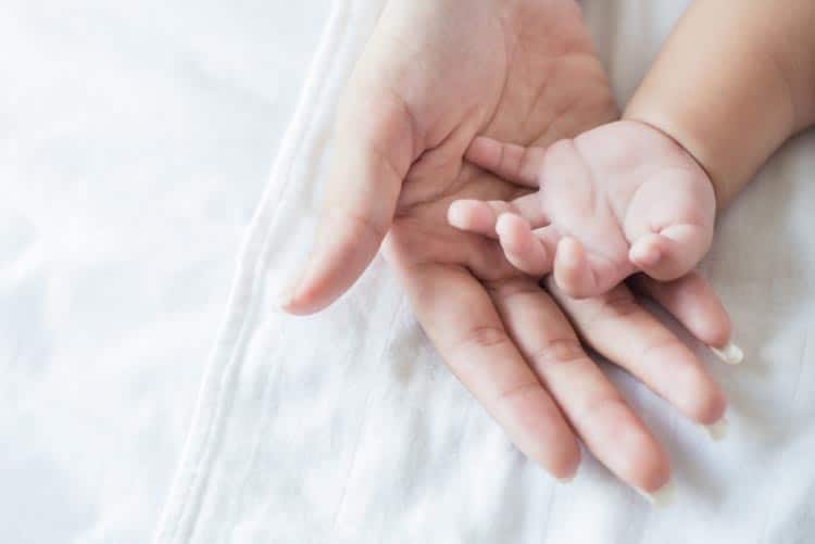 Close-up picture of the hands of a mom and her newborn