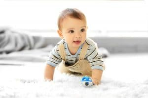 Little baby boy crawling on a rug at home.