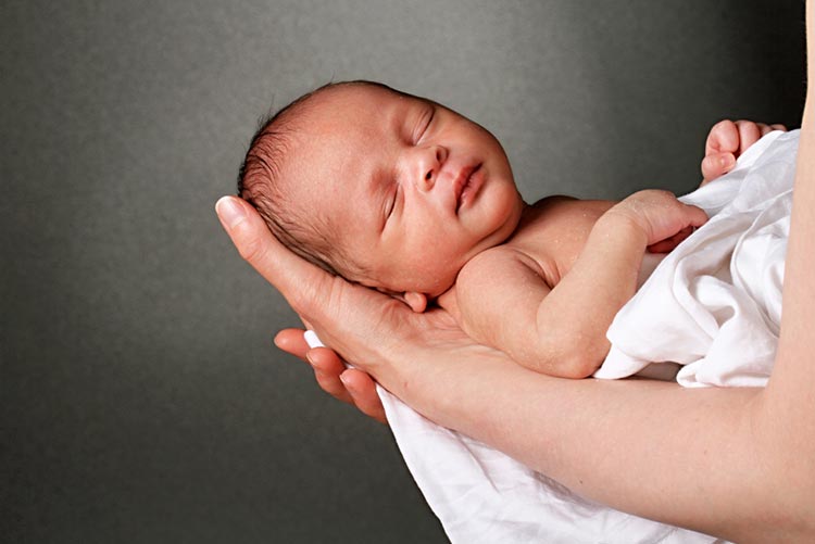 Newborn sleeping in her mother’s arms.