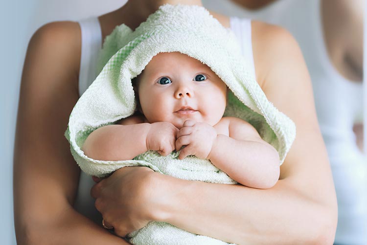 Adorable infant girl wrapped in a green towel being held by her mommy!