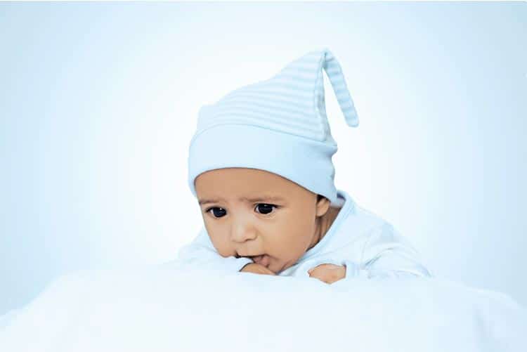 Adorable toddler wearing sky blue suit, lying on the bed.