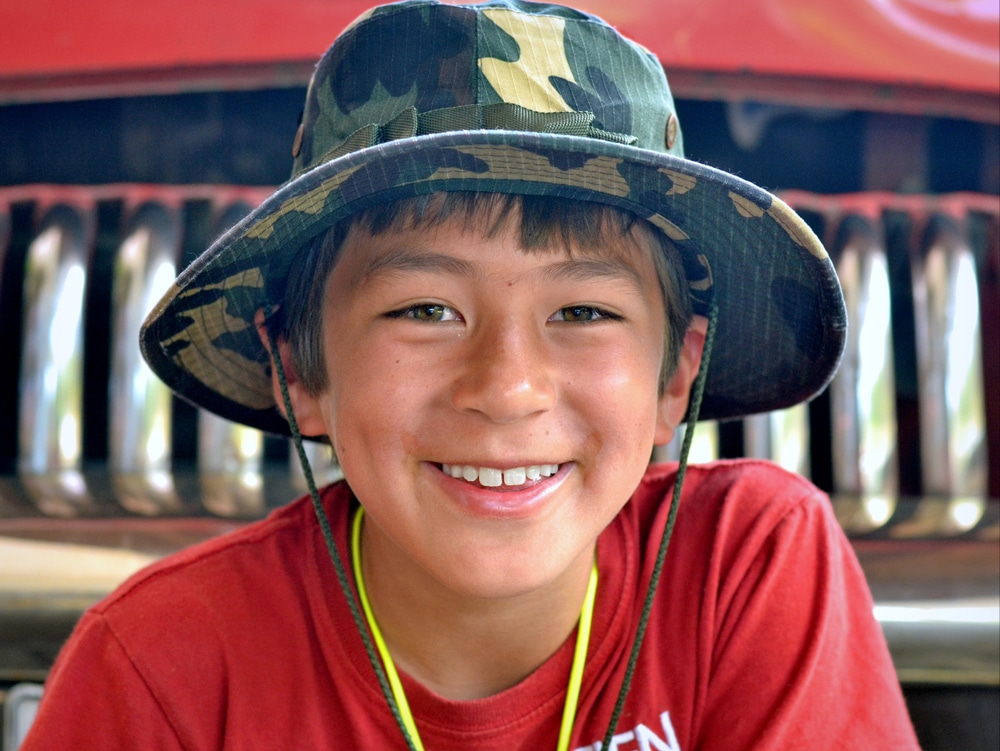 Young boy wearing a camouflage sun hat.