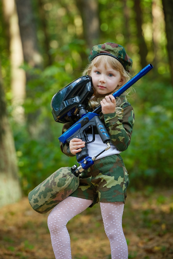 Young girl in a camo suit holding a rifle.