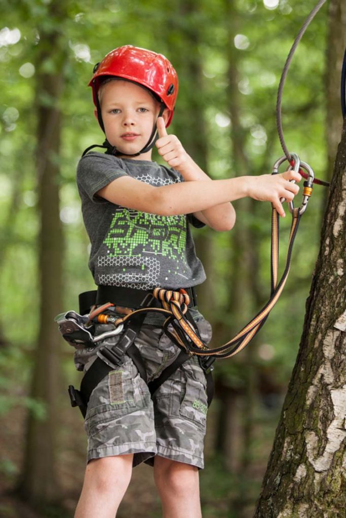 Young boy wearing camouflage shorts in a rope park.