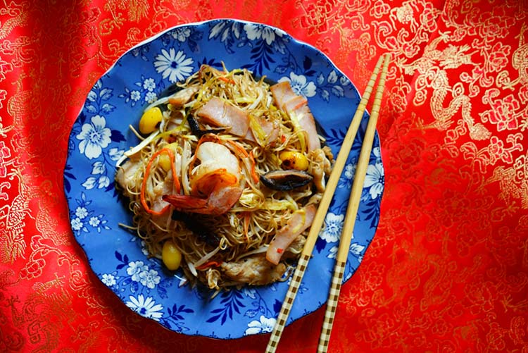 Longevity noodles made with seafood and ham served on a blue plate with chopsticks - marking the Spring Festival or Chinese Lunar New Year.
