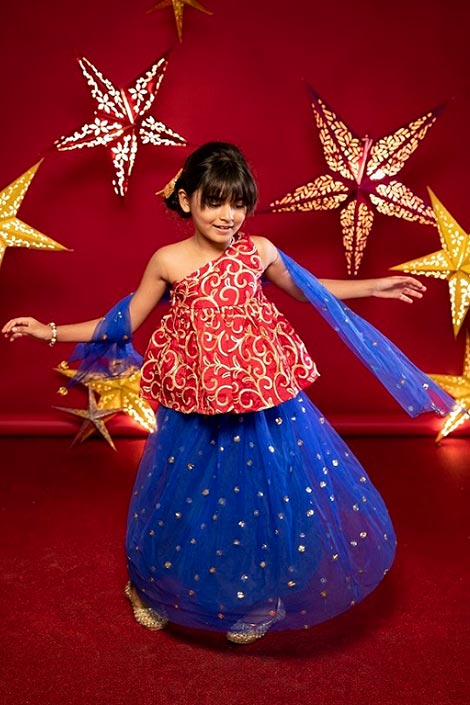 A girl dressed in a lehenga spinning around.