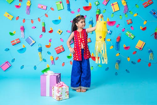 A girl wearing a salwar kameez holding up a lantern.