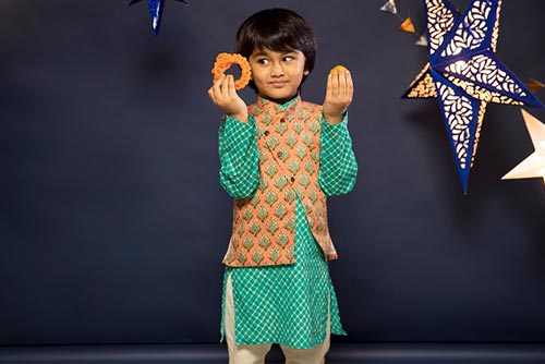 A boy, wearing a three-piece kurta set, gapes at Diwali sweets.