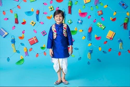A happy-looking boy wearing a bright kurta-dhoti set with a waistcoat.