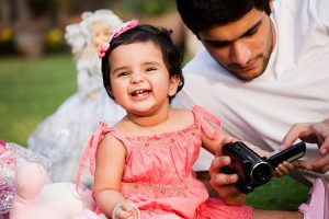 Father showing pictures on his camera to his adorable daughter.