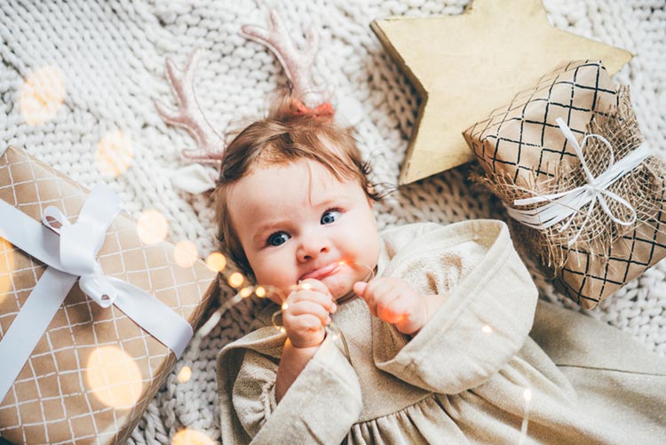 Adorable baby girl lying down amidst Christmas decorations and lights!