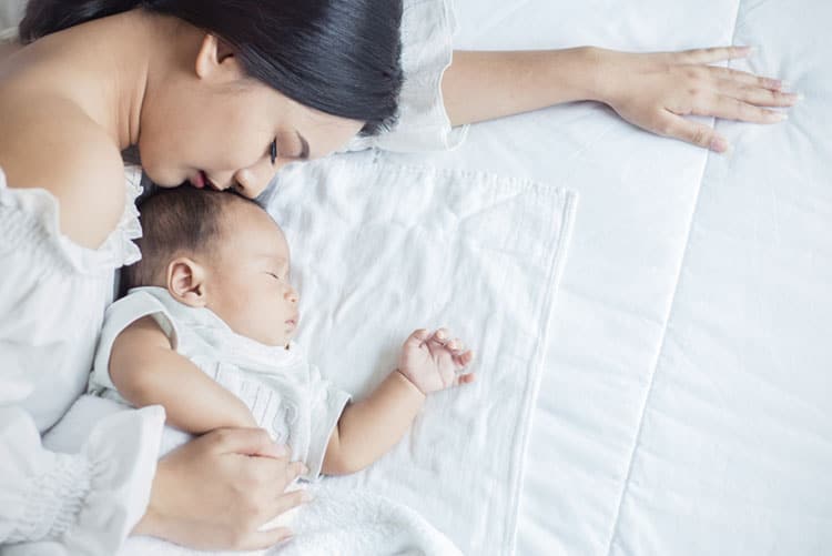 Mother sleeping with her newborn.