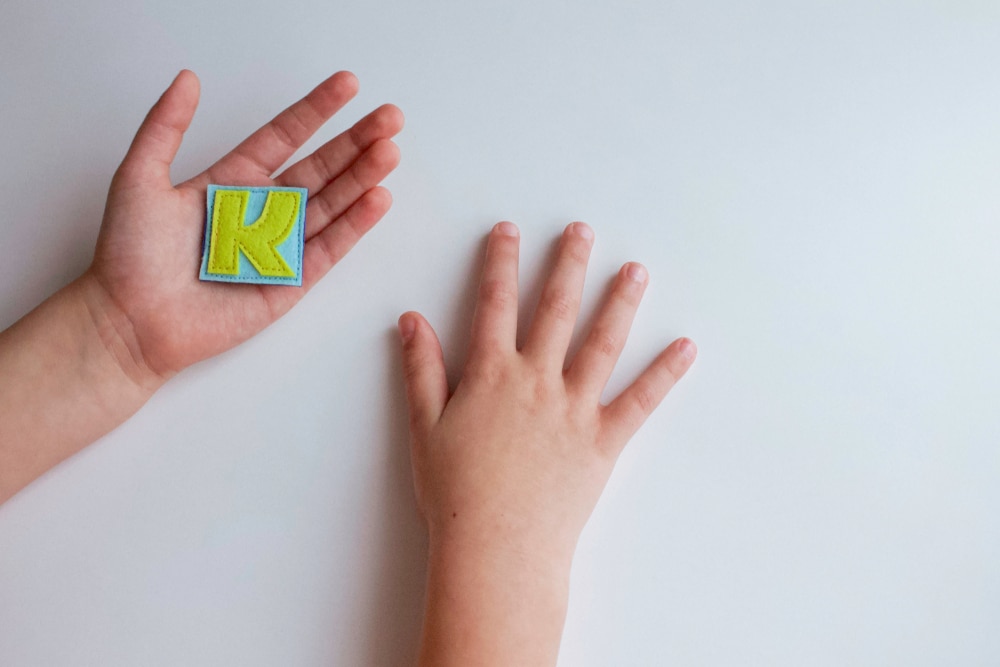Child's hand holding the letter K