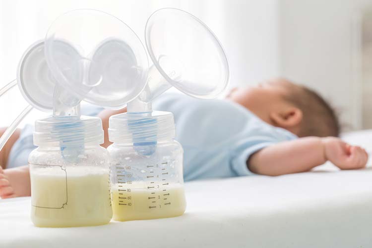 Breastmilk pump and infant on the bed.