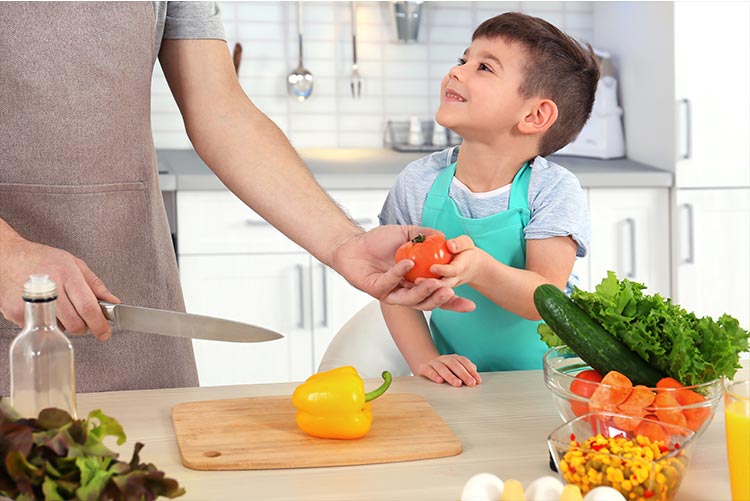 A child helps his parent in the kitchen.