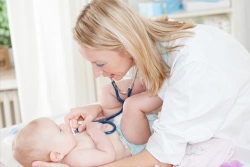 A paediatrician checking a baby’s heartbeat.