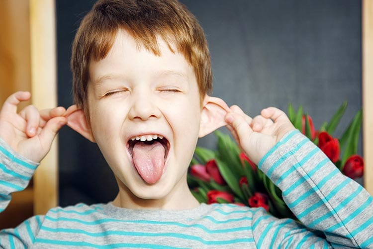 A young boy holding on to his ears.