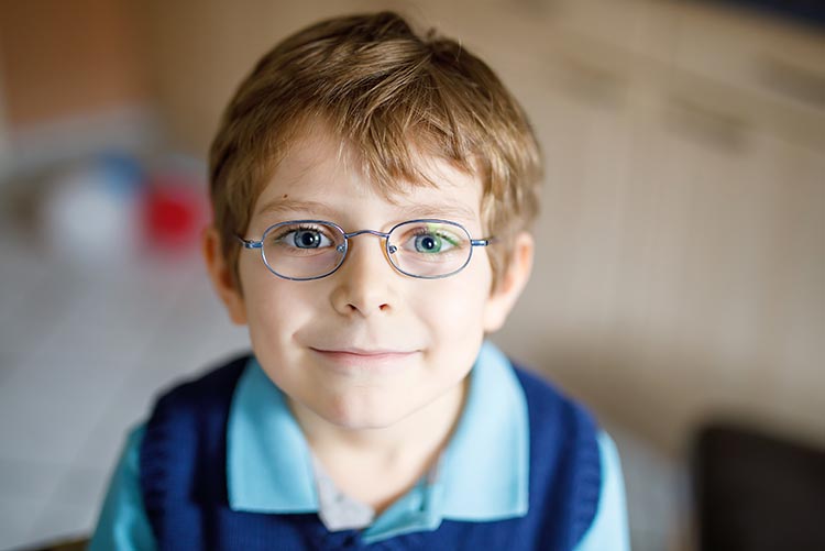 A boy wearing glasses smiling at the camera.