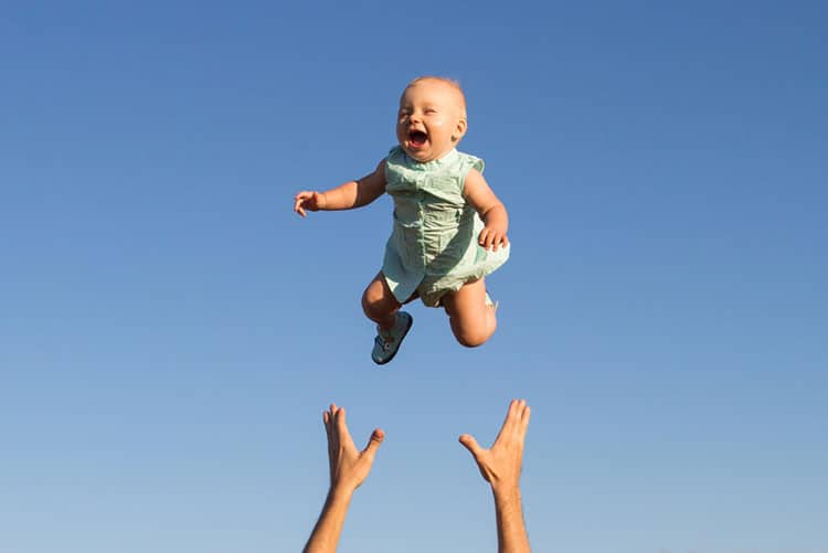 Father plays a game of throwing his baby up in the air and catching him.