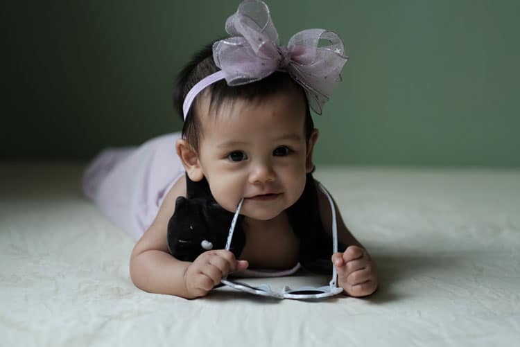 Adorably happy baby wearing a bow headband, smiling sweetly!