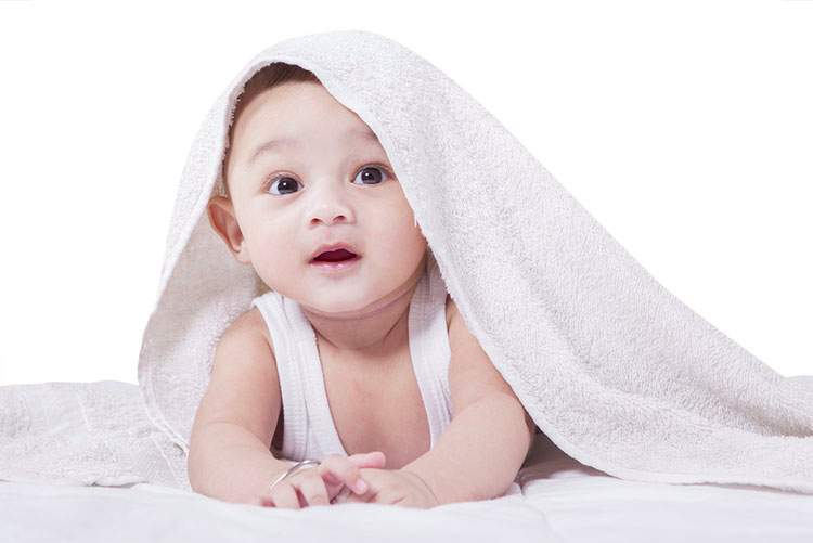 Cute baby boy lying on a bed, wrapped with a soft towel!