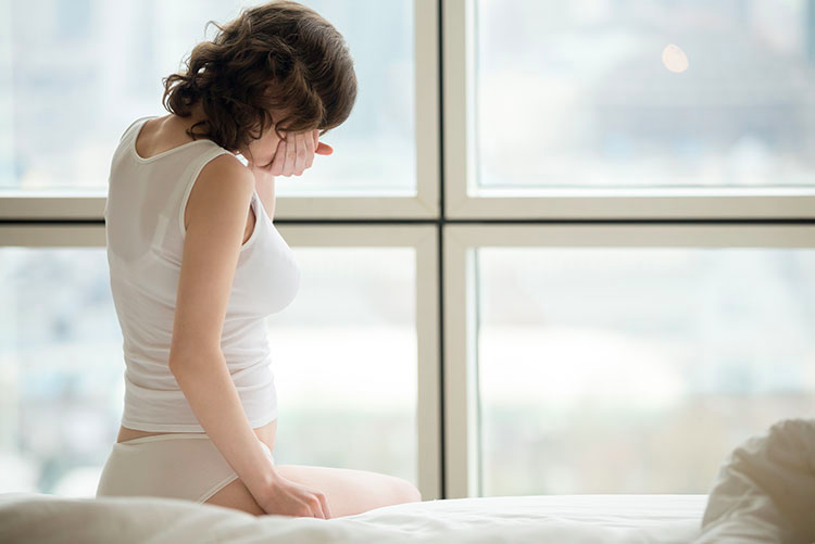 Pregnant woman sitting on her bad feeling sick.