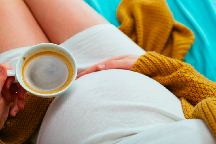 Closeup of a pregnant woman drinking coffee
