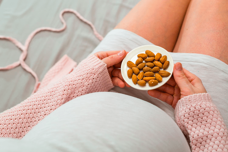 Closeup of a pregnant woman eating a bowl of almonds!
