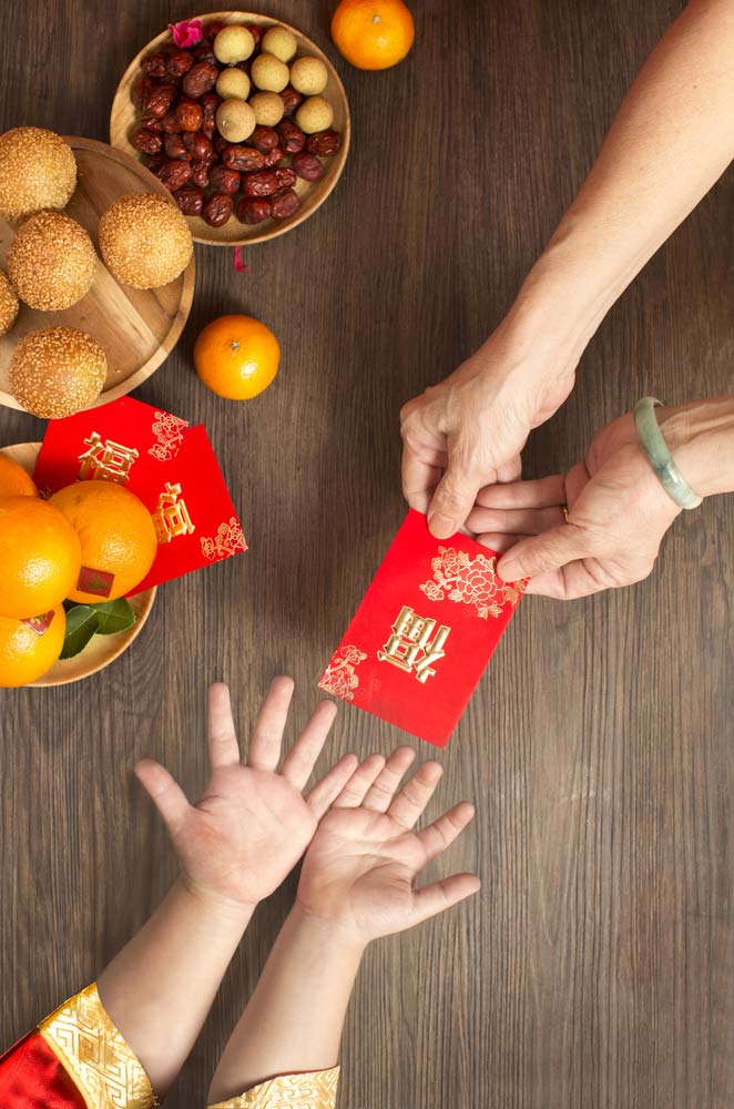 Person handing red packet to a child